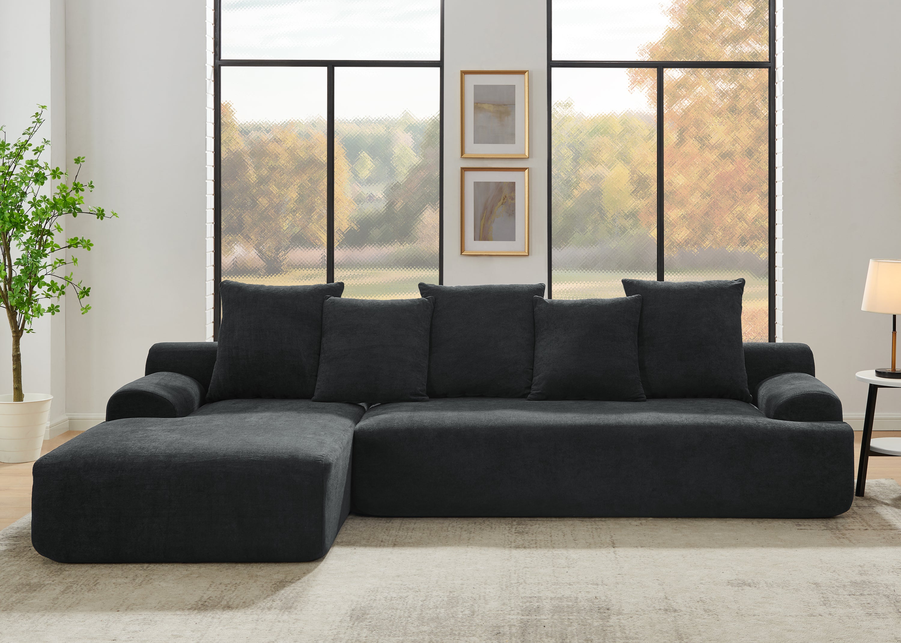Contemporary black velvet modular sofa in a living room with large windows and a plant.
