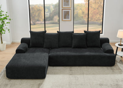Contemporary black velvet modular sofa in a living room with large windows and a plant.