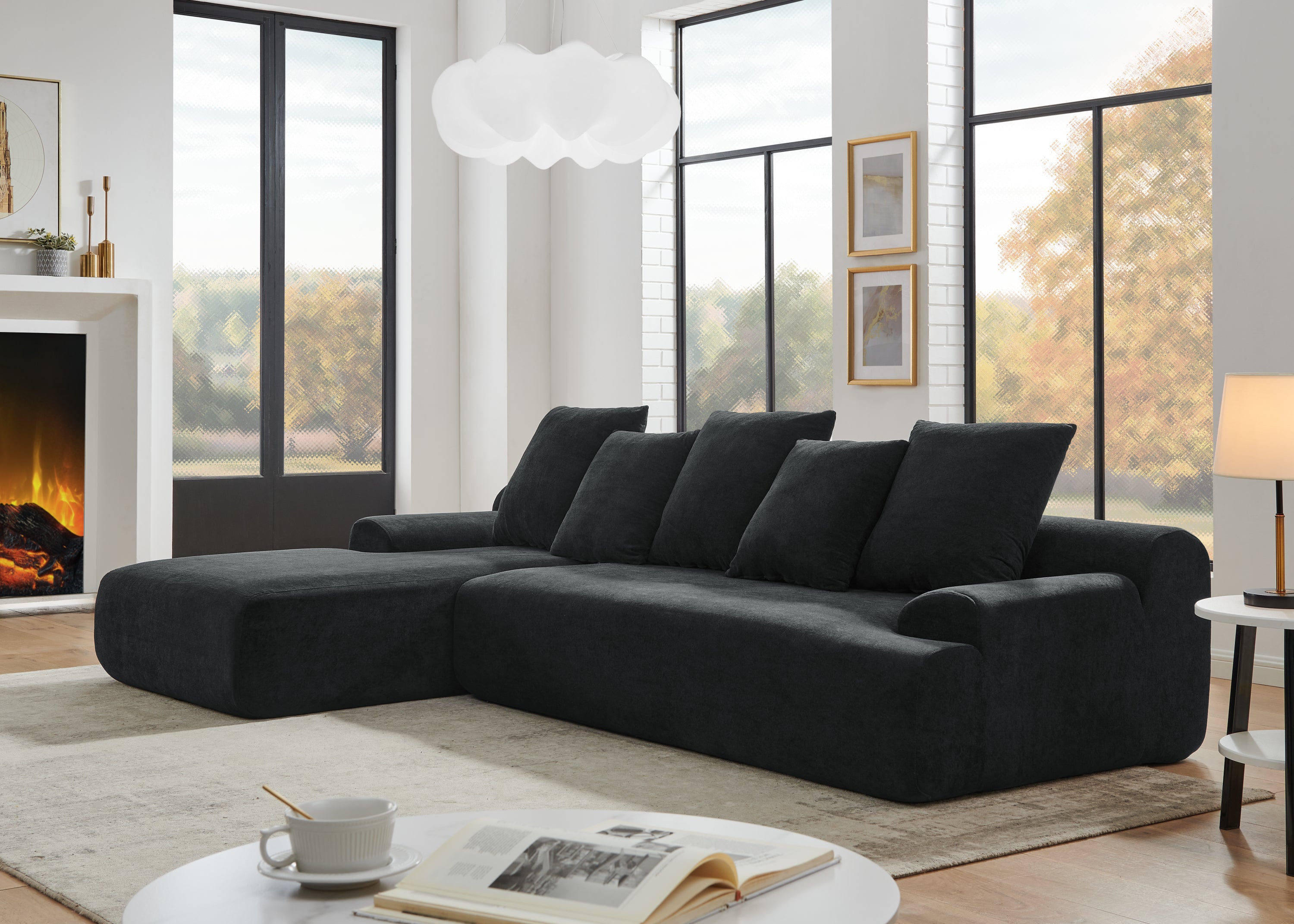 Contemporary black velvet modular sofa in a living room with large windows and a plant.