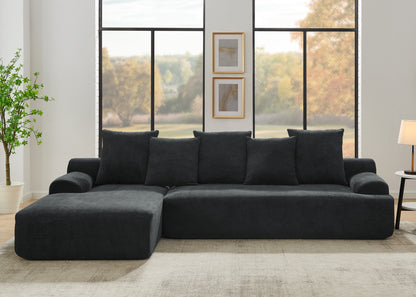 Contemporary black velvet modular sofa in a living room with large windows and a plant.